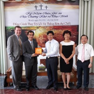 Hien Vu and the IGE team with pastor Nguyen Huu Mac, president of Evangelical Churches of Vietnam-North, a denomination with 1,000 churches throughout northern Vietnam. Pastor Mac gave them a plaque of the Hanoi Bible College (the only formally recognized Protestant college/seminary in the north of Vietnam) which graduated its first students. IGE, among others, engaged the government for many years, arguing that people of faith should be able to teach their own theology which would also produce better citizens that serve the elderly and orphans while providing a moral bulwark against corruption..